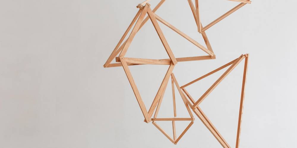 Hölzerner geometrischer Dekor der vor weißem Wandhintergrund hängt