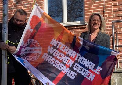 Anja Kerl hisst die Fahne zum Start der Internationalen Wochen gegen Rassismus. / Landkreis Rostock