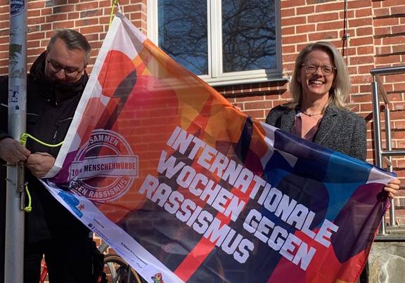 Anja Kerl hisst die Fahne zum Start der Internationalen Wochen gegen Rassismus. / Landkreis Rostock