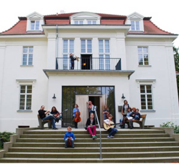 Musikschülerinnen und Musikschüler vor der Rückansicht des Musikschulgebäudes in Bad Doberan