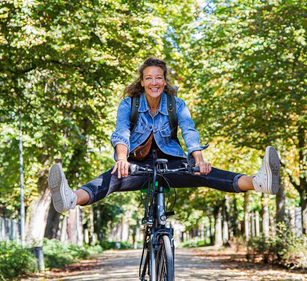 Frau auf einem Rad streckt die Beine zur Seite