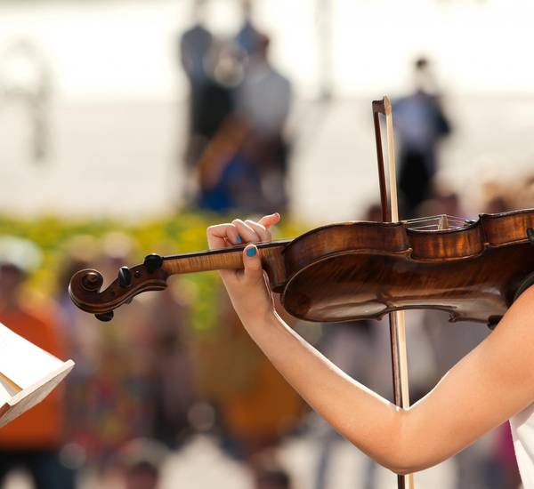 Eine Violine in der Hand eines Menschen mit lackierten Fingernägeln